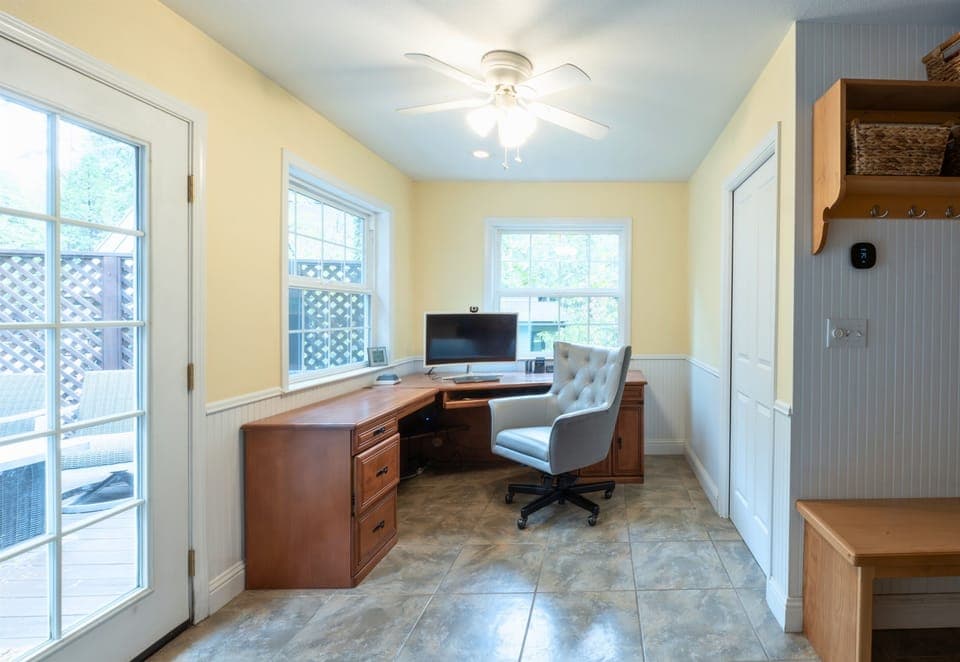 A bright home office space with a large desk, comfortable chair, and abundant natural light, perfect for work or study.