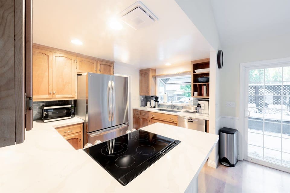 Clean and modern look with white countertops, stainless steel appliances, and wooden cabinetry.