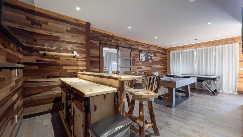 Game room with bar top, large tv, pool table, air hockey, and multicade. 