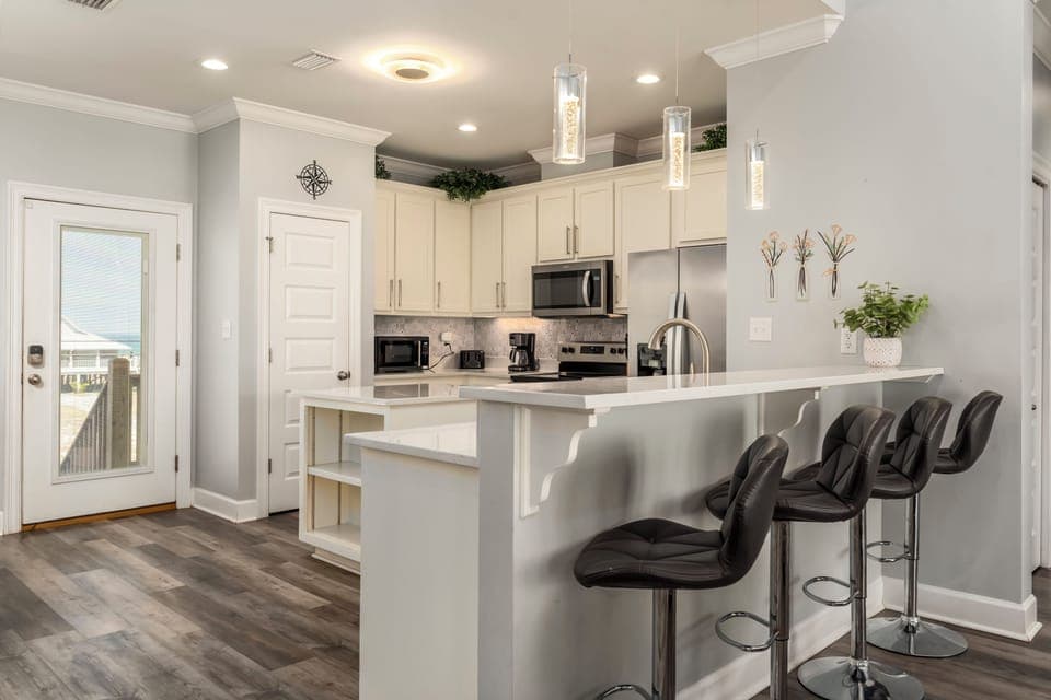 Your fully equipped kitchen features sleek white cabinets, stainless steel appliances, and a breakfast bar perfect for morning coffee or quick meals.