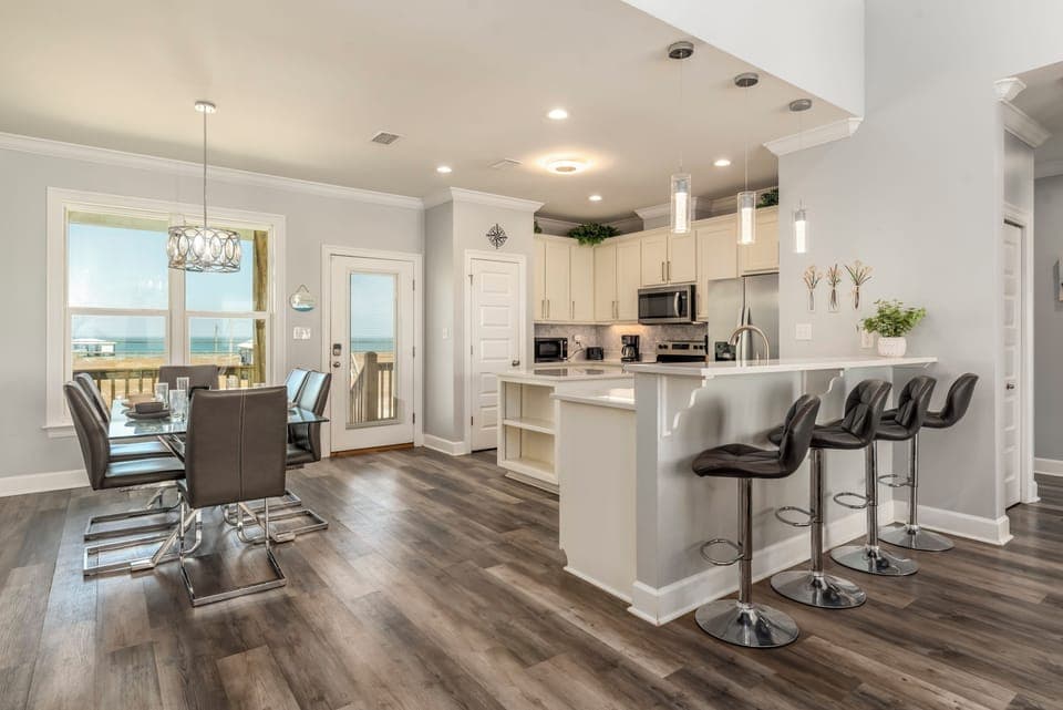 Your modern kitchen flows seamlessly into the dining area, where ocean views through the windows create the perfect backdrop for memorable meals.