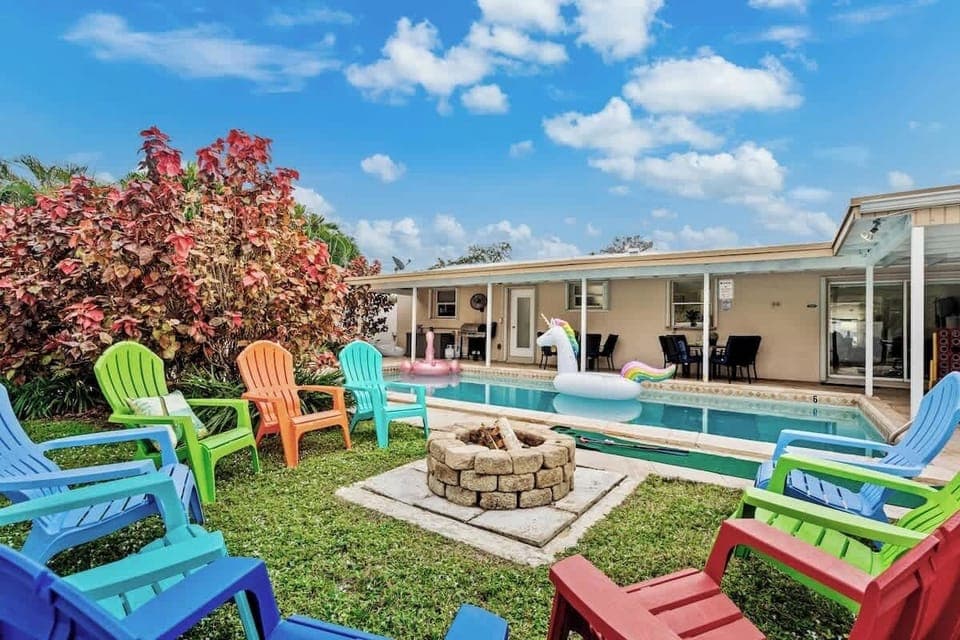 - Backyard fire pit with colorful chairs surrounding the pool  
- Relax by the water with unicorn floaties and open skies  
- Outdoor setup perfect for gatherings and evening fun  