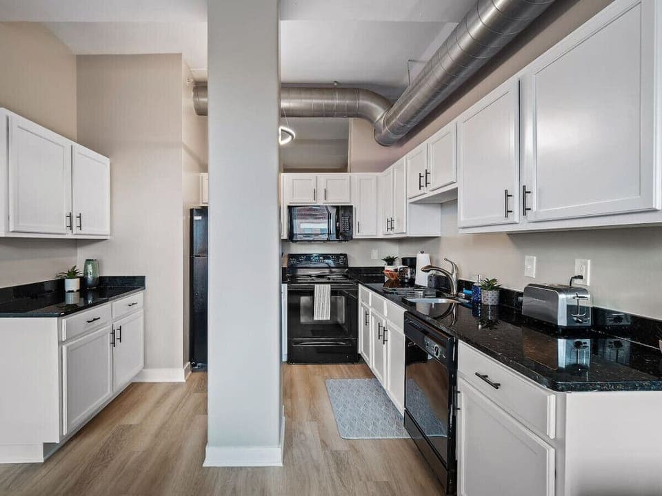 Fully equipped kitchen with modern appliances   - Spacious counters with sleek black granite finish   - White cabinetry offers style and practical storage