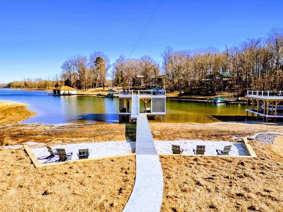 Your Private Beach Landing – Adirondacks in the sand, calm water ahead, and a dock just steps away.