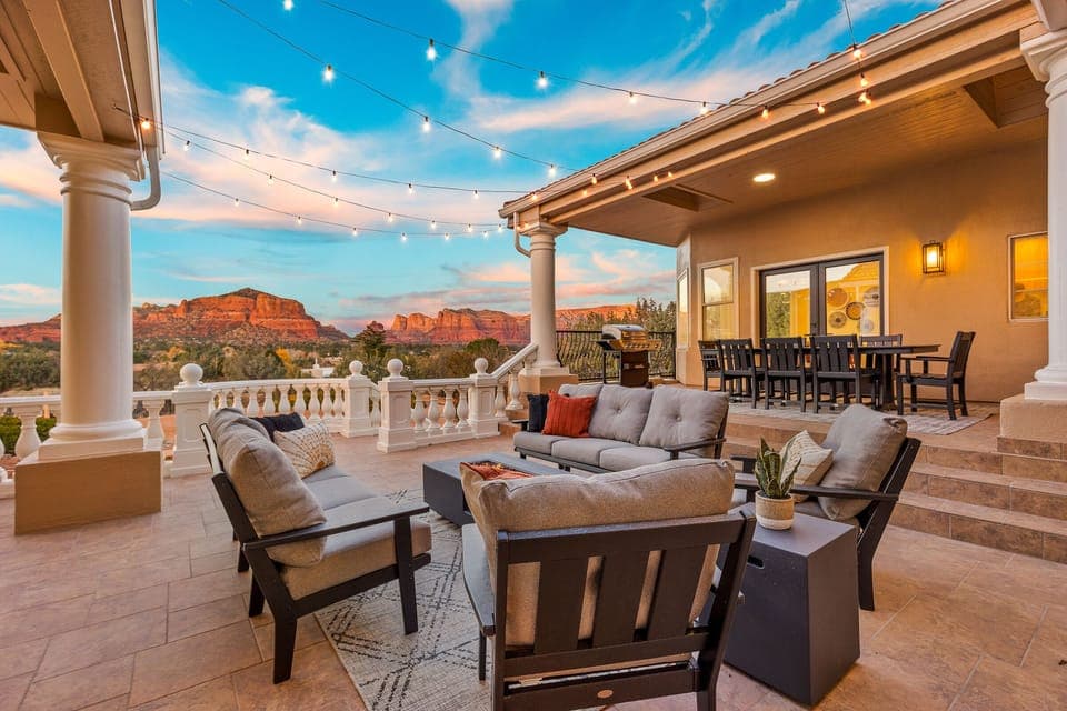 Expansive private patio with outdoor dining, lounge seating, and glowing string lights overlooking Sedona’s iconic red rocks.