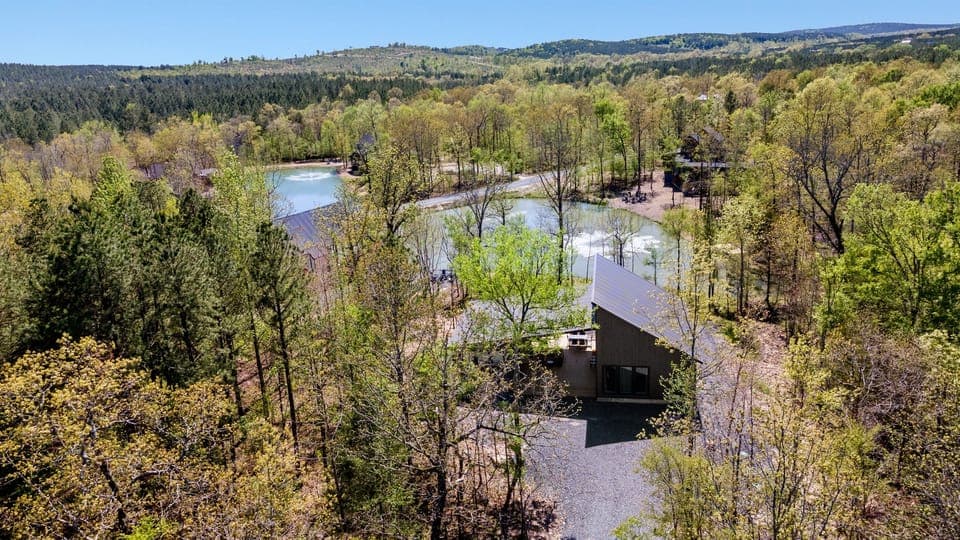 Elevated view of a sleek waterfront abode amidst a sprawling landscape, bridging modern living with nature.
