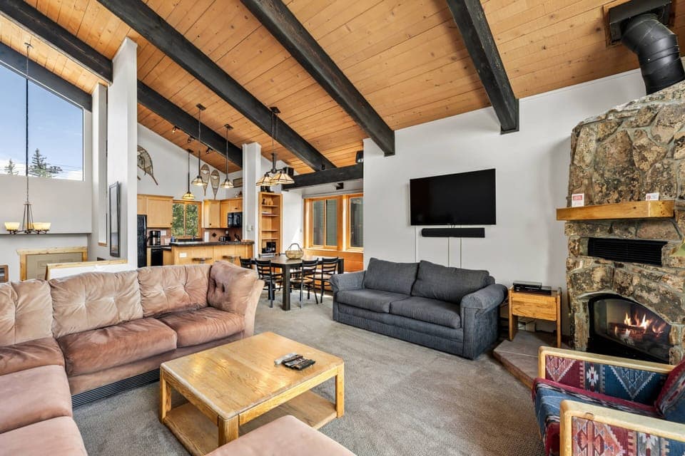 Spacious and inviting mountain retreat with vaulted ceilings, a warm stone fireplace, and an open living area perfect for relaxing and entertaining.