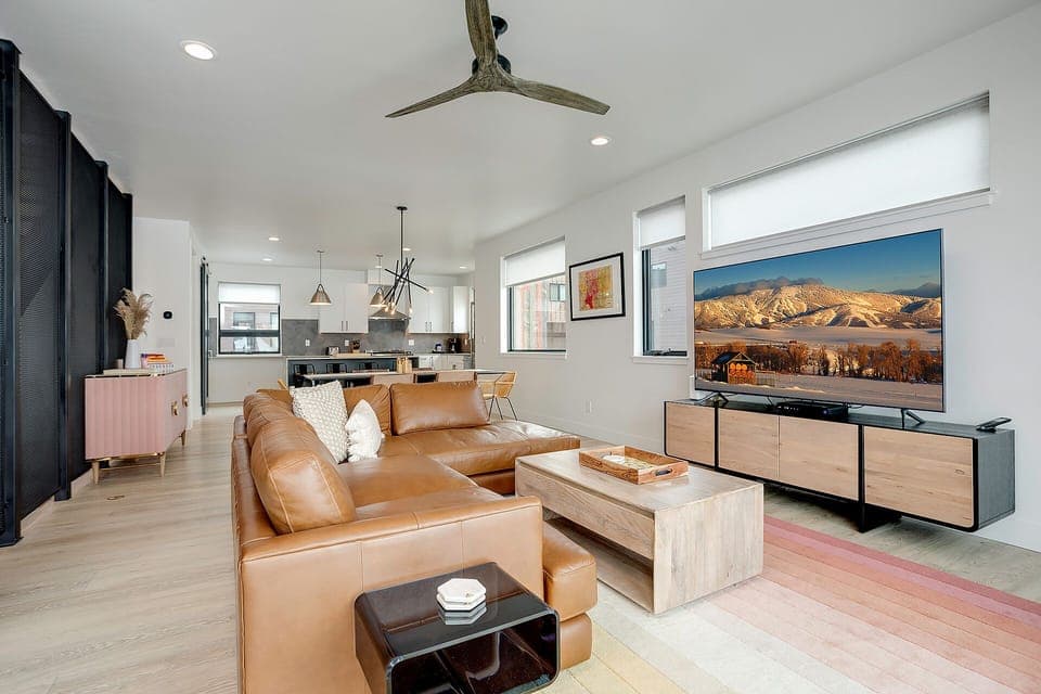 Relax in this stunning open-concept living space with luxurious leather seating, modern kitchen, and breathtaking mountain views from your windows.