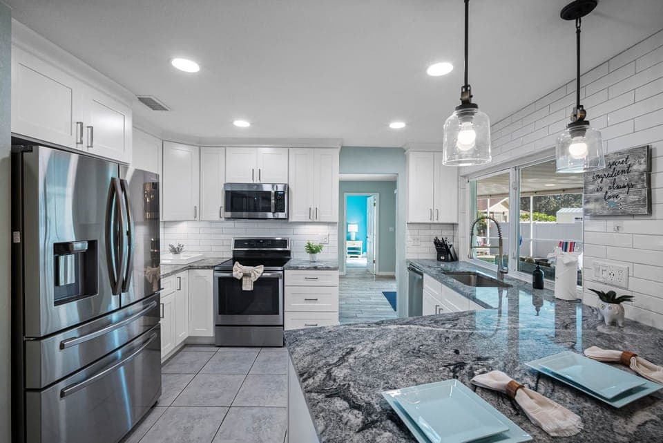 This modern kitchen blends style and function, featuring a spacious layout, bar seating, and plenty of natural light.