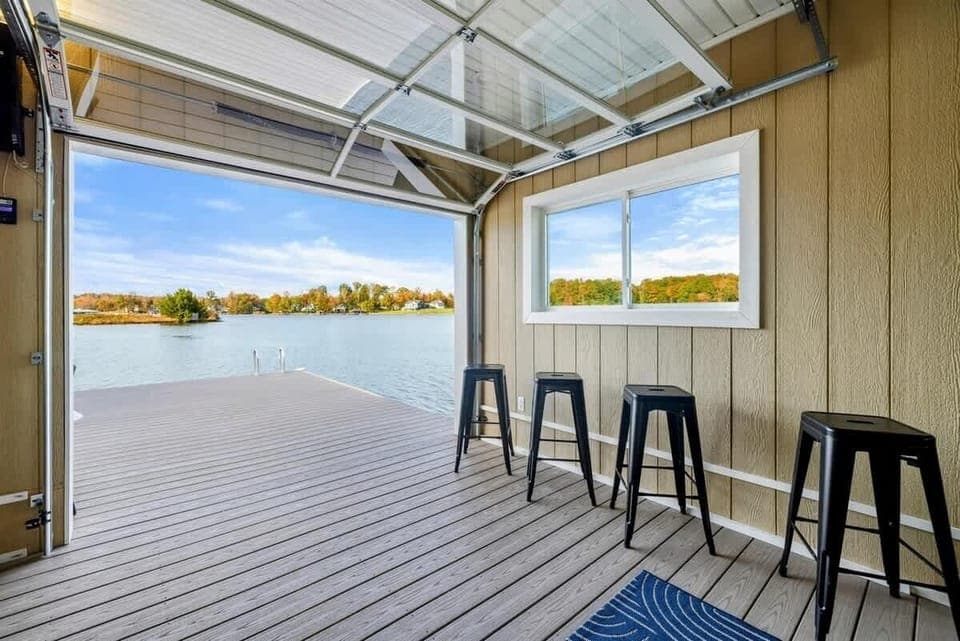 A serene lakeside space with a bar area and a fully retractable glass door that opens directly onto a spacious dock