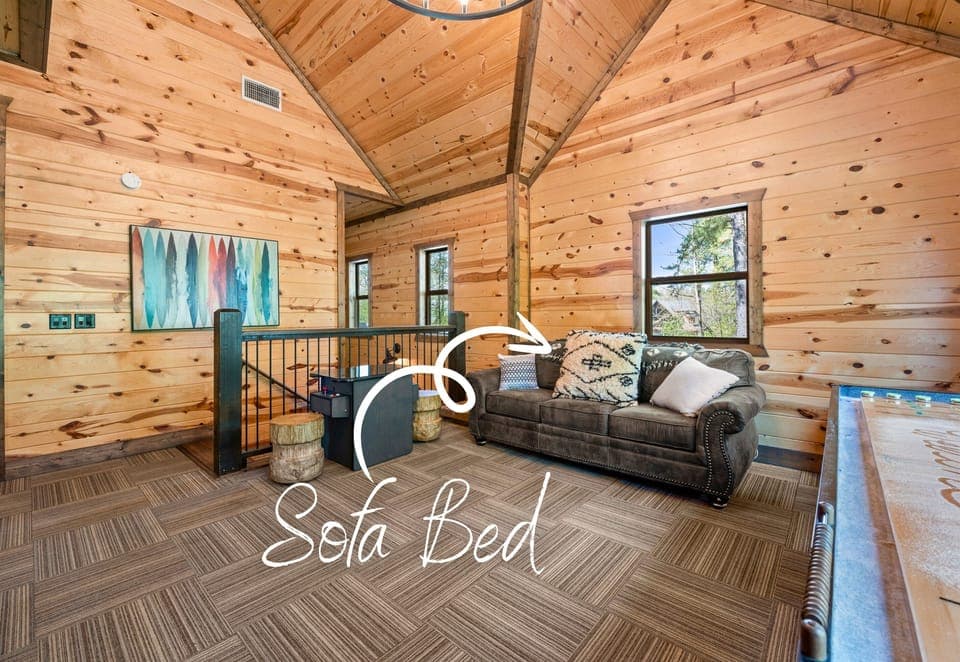 Nestled in a high-ceiling log cabin space, this cozy living room features a comfortable sofa bed.