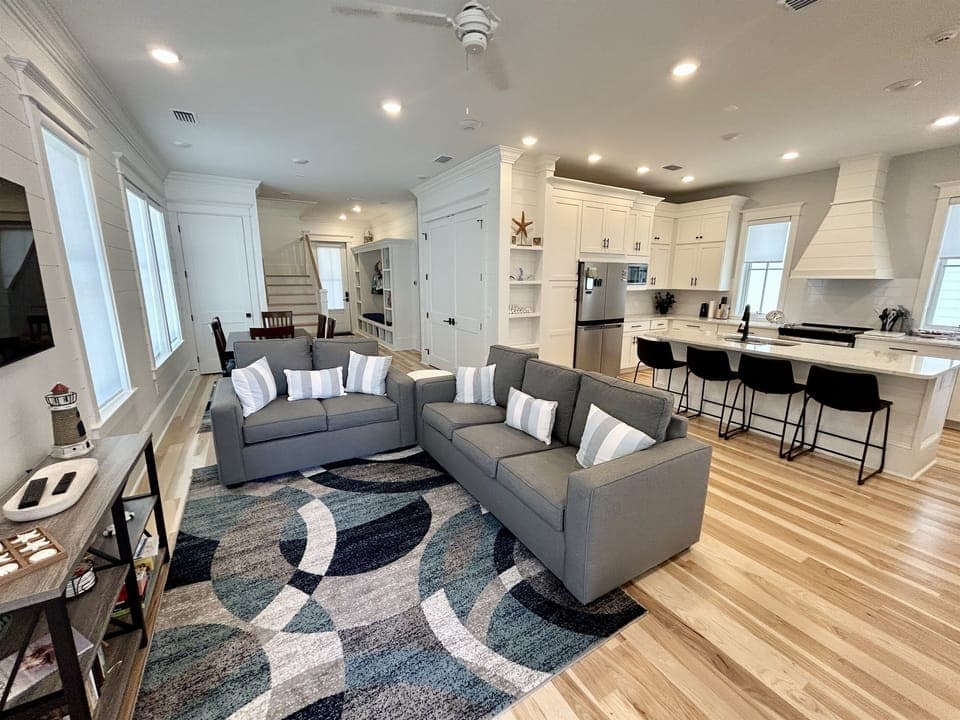 Relax in your bright, open living space where modern comfort meets coastal charm, with plush seating flowing into a chef's kitchen.