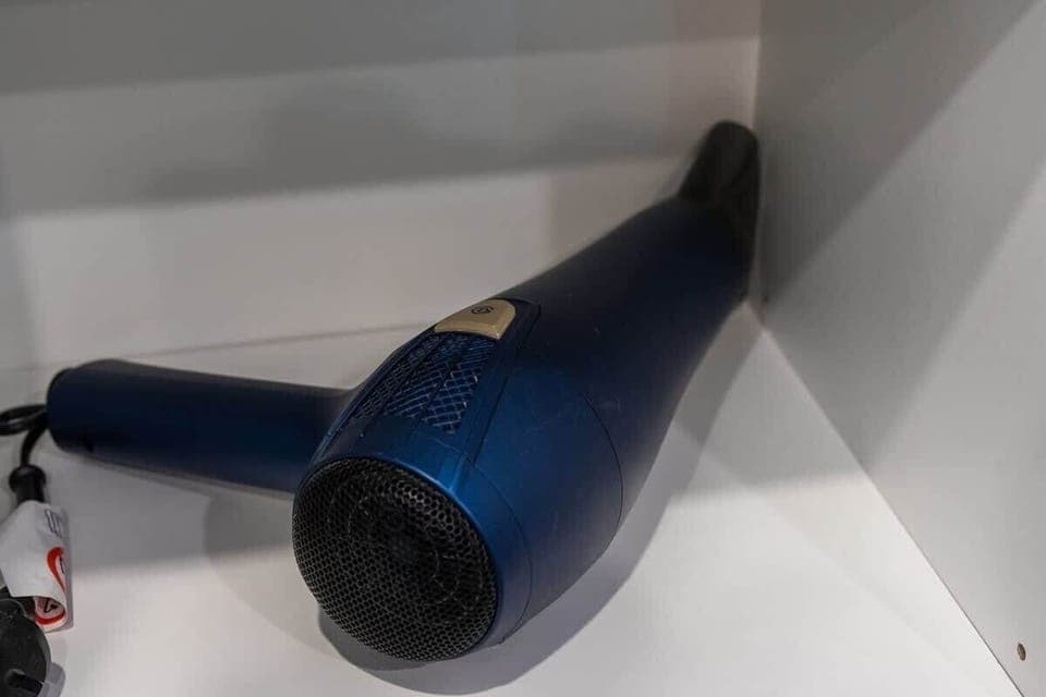 A black hairdryer stored in a cabinet, providing convenience for guests.
