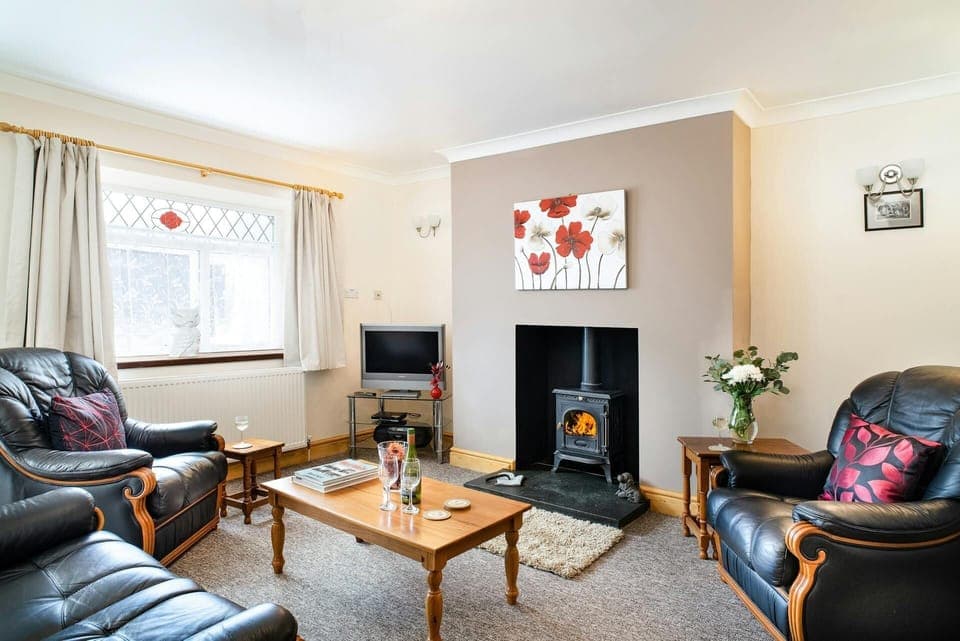 Lounge with sofa, armchairs, open fireplace with woodburner, tv