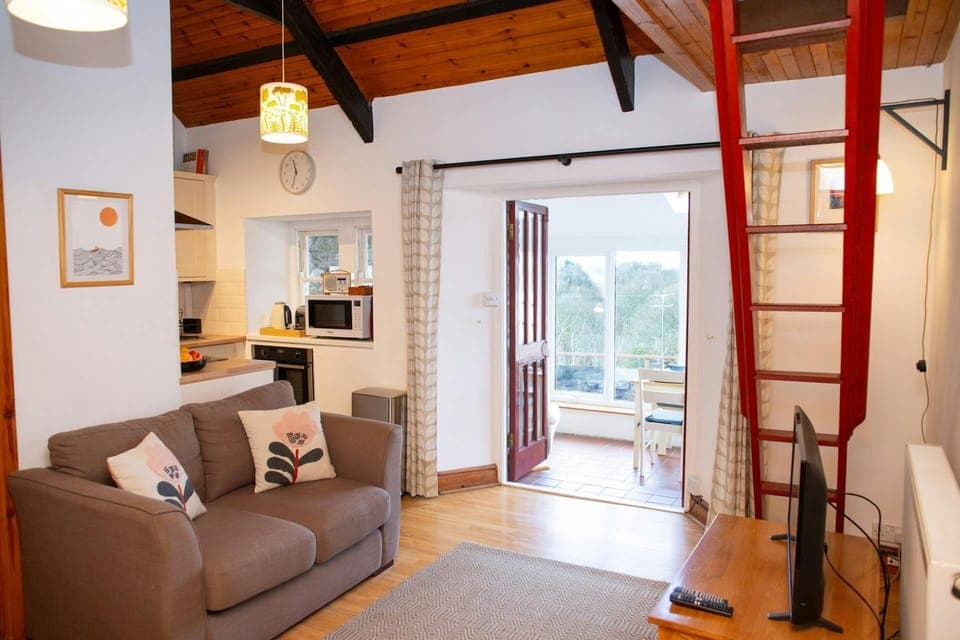 Lounge with steps to mezzanine, sofa, tv, kitchen area