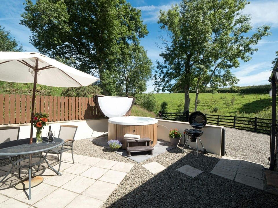 Patio with table, chairs, parasol and hot tub