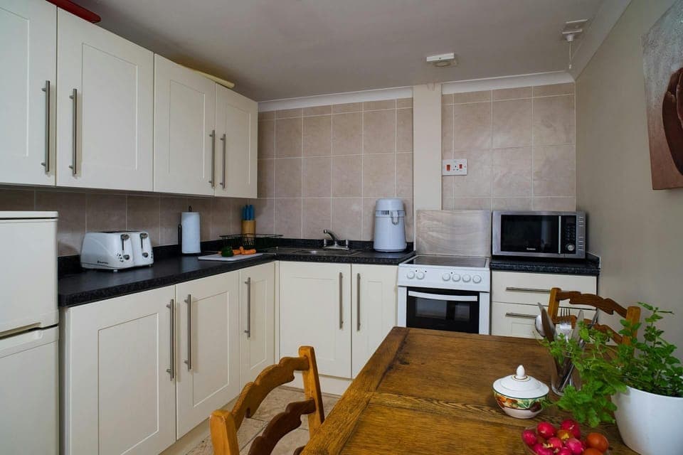 Fitted kitchen at Min y Graig with cooker, fridge and dining table