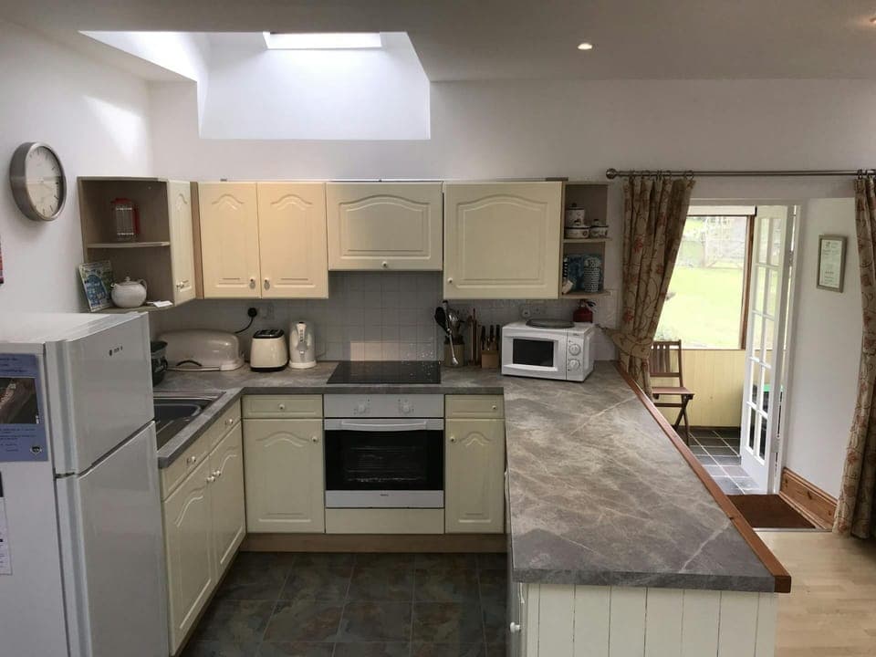 Kitchen with fridge/freezer, cooker, microwave, toaster, kettle, sink, doors into conservatory