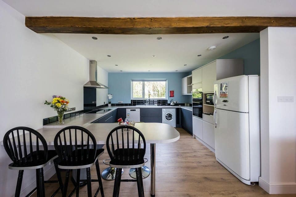 Kitchen with dining table, washing machine and fridge.