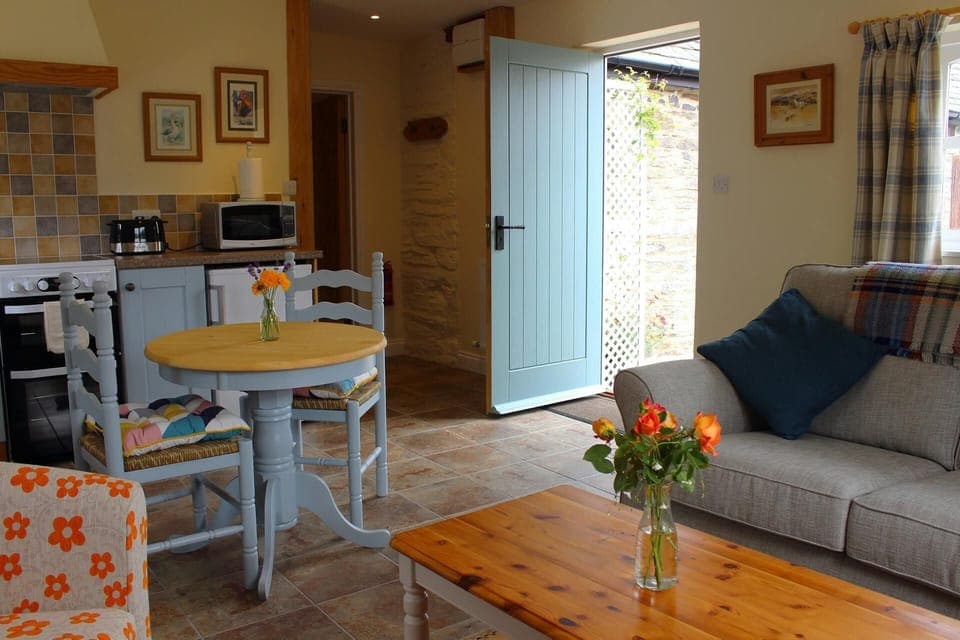 Table and chairs, coffee table, sofa, door to garden and flowers in a vase