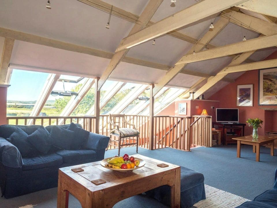 Lounge area with beamed ceiling, sofa, coffee table and TV