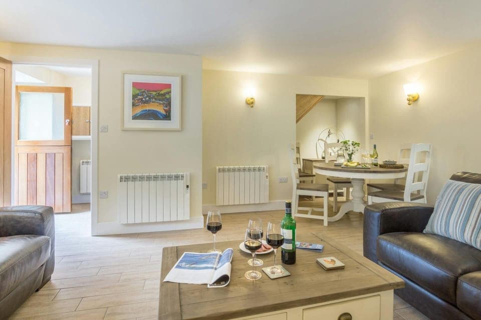 Living/dining area: two leather sofas, coffee table, dining table with four chairs