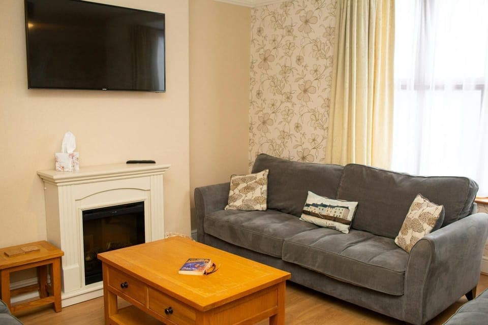 Wall mounted TV above the fireplace. Large sofa and coffee table