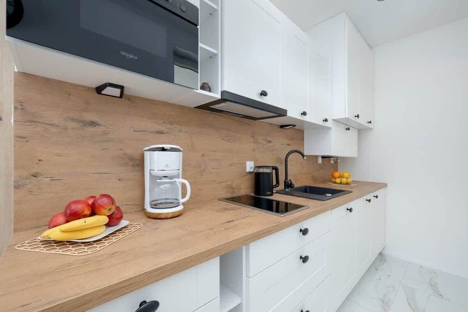 A close-up of the modern kitchen, featuring white cabinets, a wooden countertop, and basic appliances like a kettle and toaster. The kitchen is fully equipped, with fresh lemons adding a touch of color to the counter.