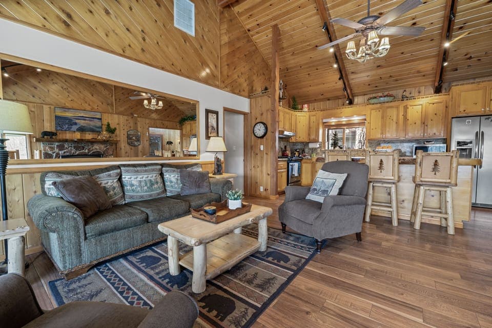 Living Room - The living room is cozy & charming w/mountain décor & comfortable furniture. This space includes a gas fireplace, dining area w/table, 55" Smart TV, lovely lake & mountain views & French doors to the backyard patio.