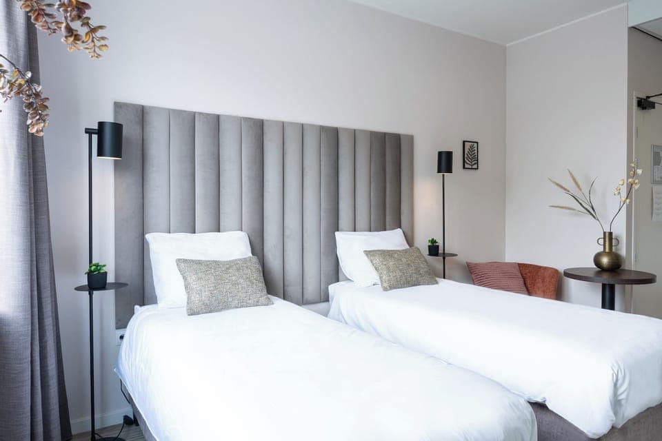 Comfortable twin beds with elegant headboards, complemented by soft lighting and a stylish seating area for relaxation.