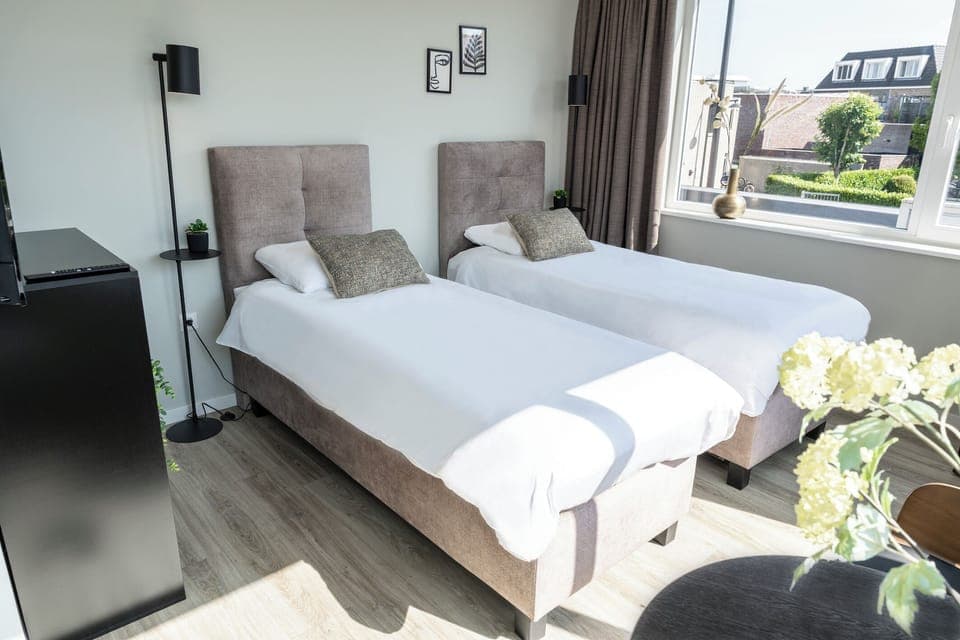 Bright twin bedroom with soft linens, cozy pillows and warm natural light — a comfortable space to relax in Raamsdonksveer.