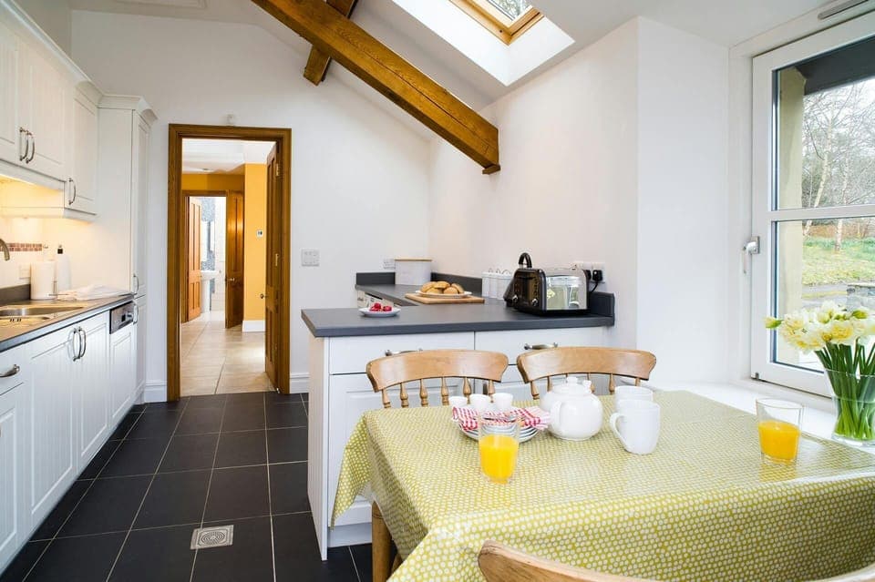 Dining table, chairs, vase of daffodils, kitchen cabinets