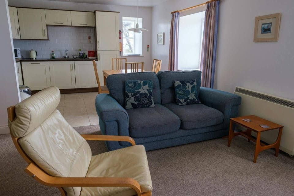 Lounge area with sofa, armchair and coffee table leading to the fitted kitchen