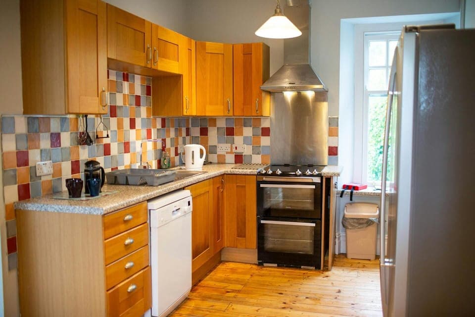 Electric cooker with extractor hood. Tiled walls and wood floor