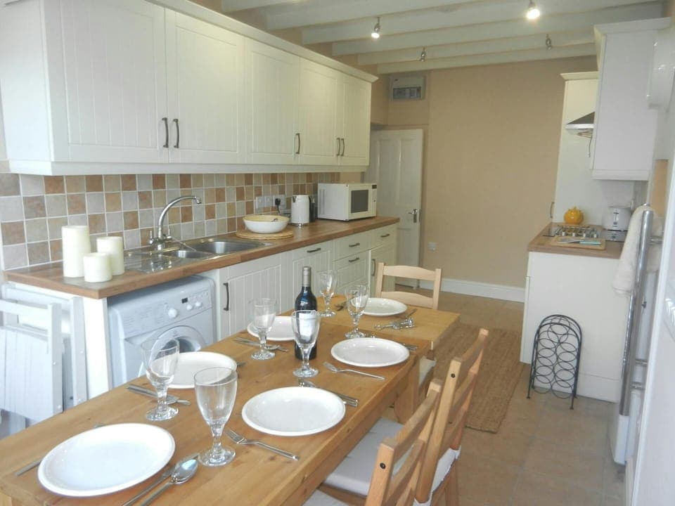 Kitchen and dining area with table and chairs, washing machine, sink and cooker