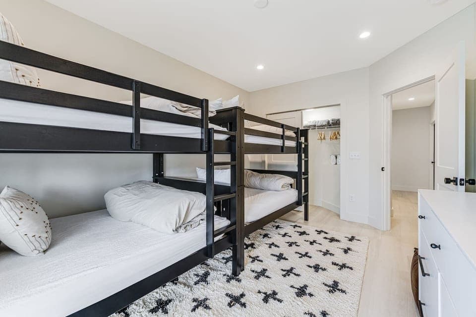 Corner view of Bedroom 5 downstairs with 4 twin bunk beds, large closet space, Smart Roku TV, and dresser