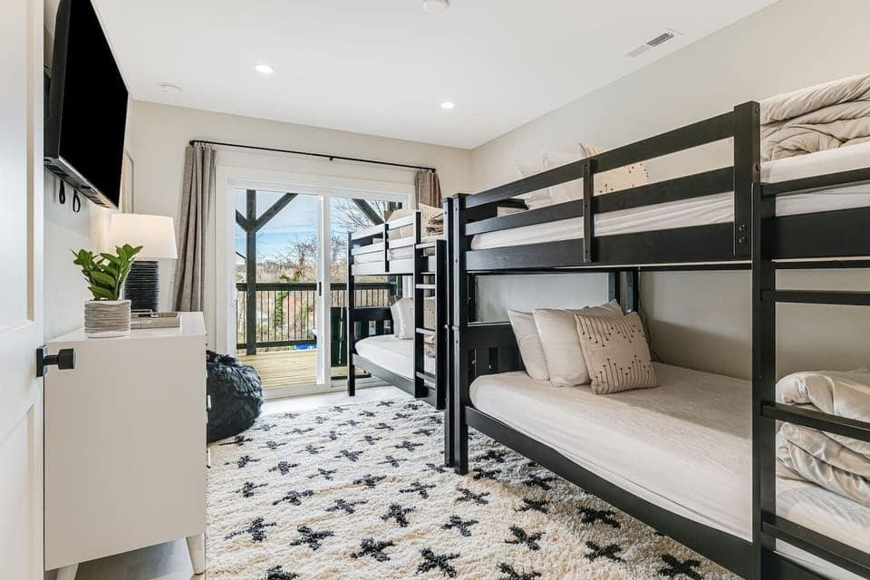 Corner view of Bedroom 5 downstairs with 4 twin bunk beds, large closet space, Smart Roku TV, and dresser