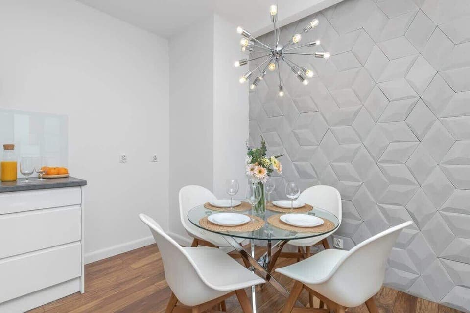 A compact, white kitchen and dining space with a modern round table and chairs.