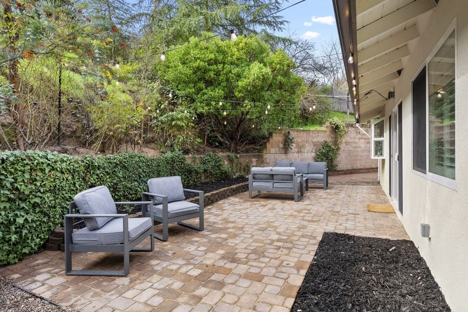 Relax in style on this modern paved patio, featuring chic grey seating and a cozy, secluded garden feel.