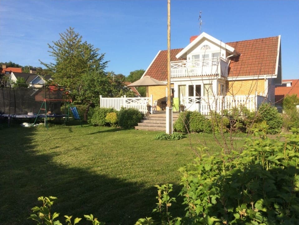 Framsidan med stor trädgård och studsmatta.