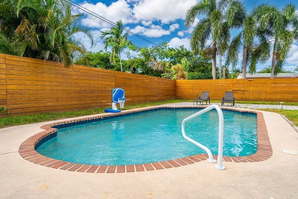 Serene pool view with lush surroundings, elegant outdoor seating .