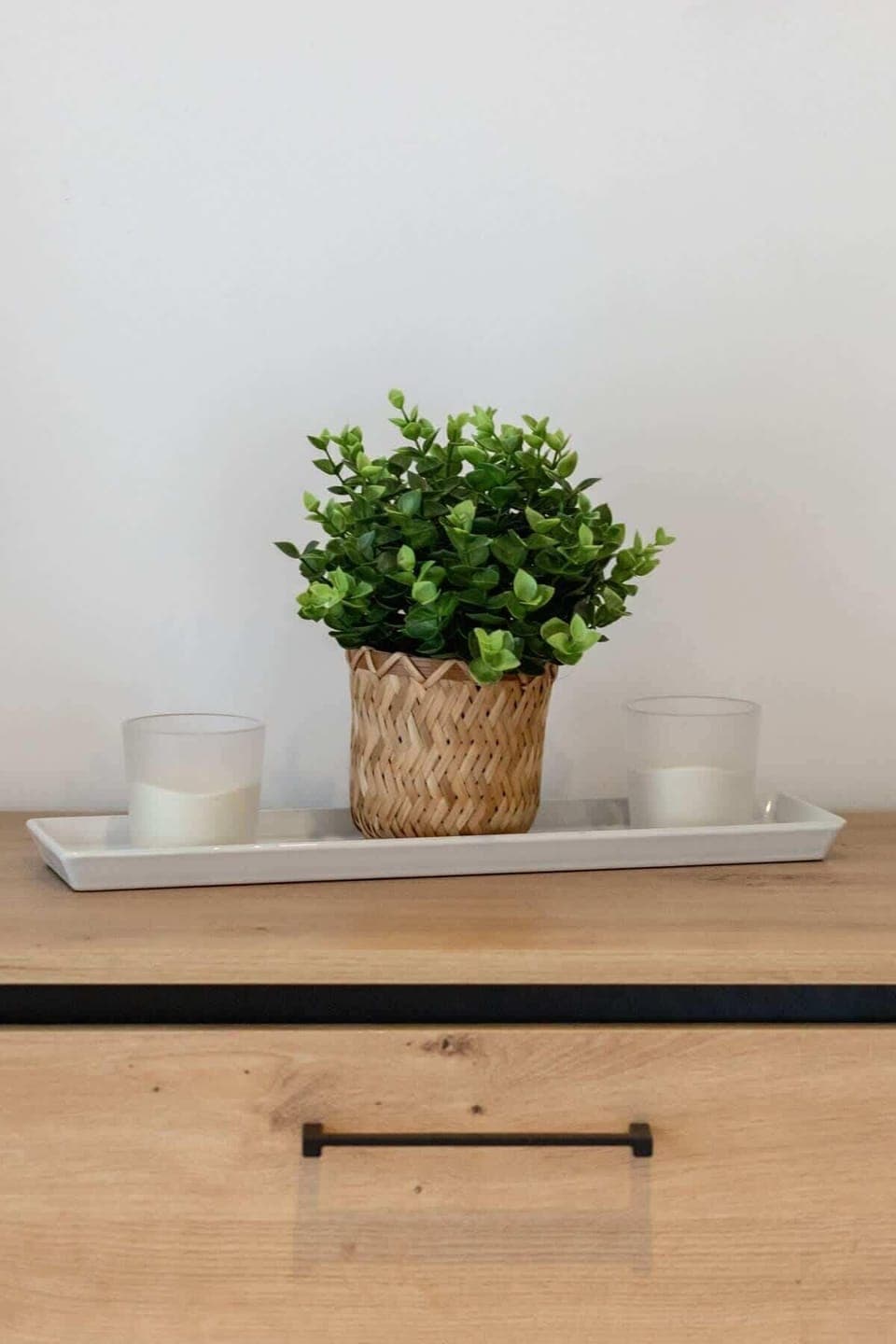 A decorative pot with a green plant placed on a wooden dresser, adding a natural touch to the interior.