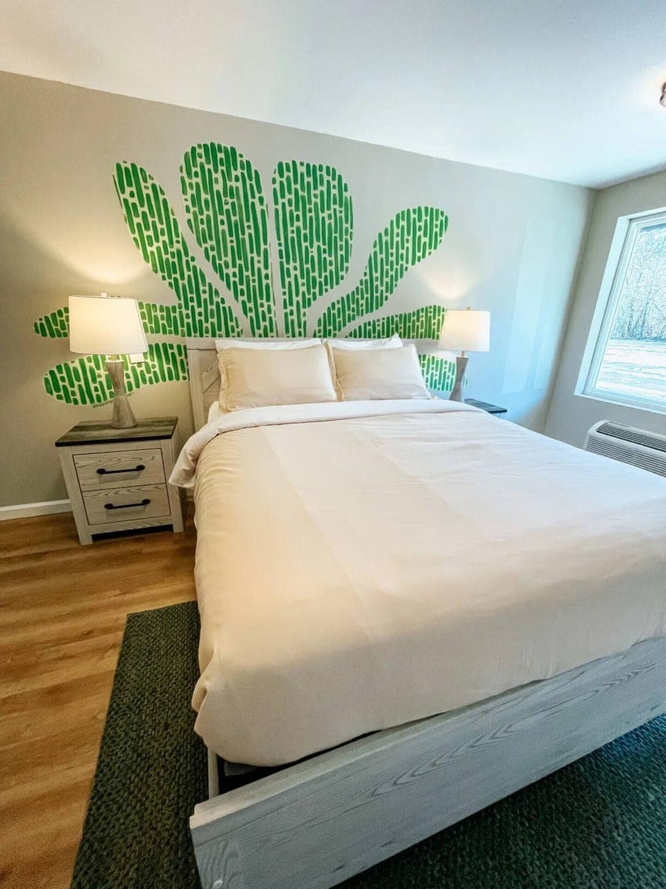 Dreaming of snuggling up in a cozy white bed surrounded by a lush green cactus mural 