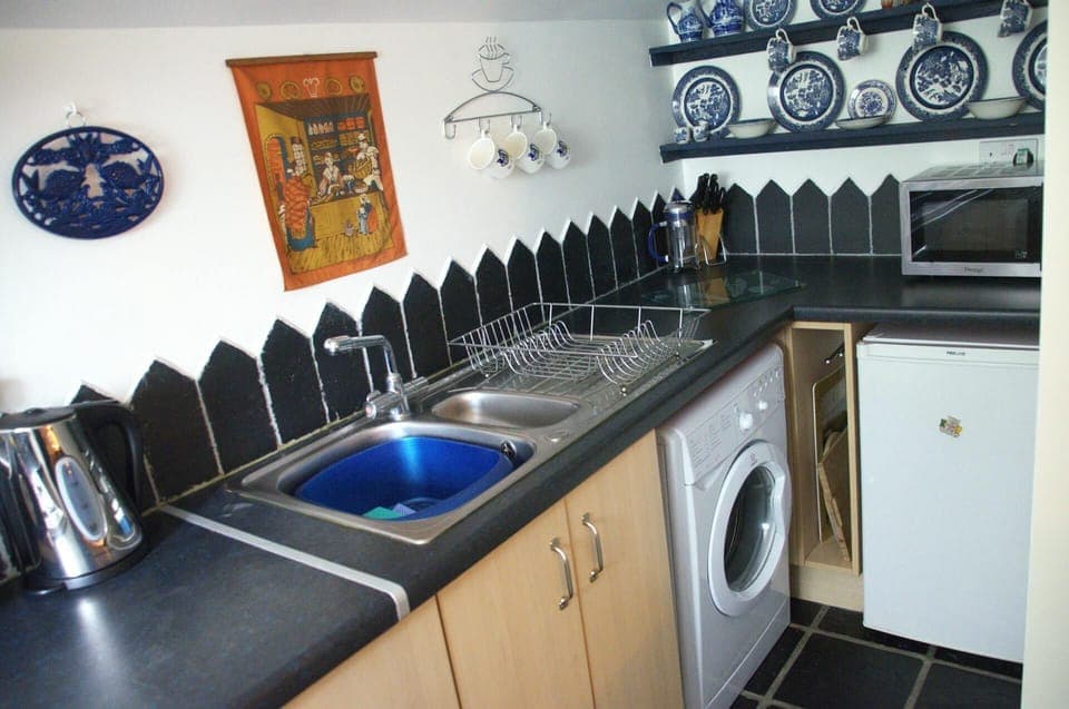 Fitted kitchen with washing machine, fridge, microwave and kettle