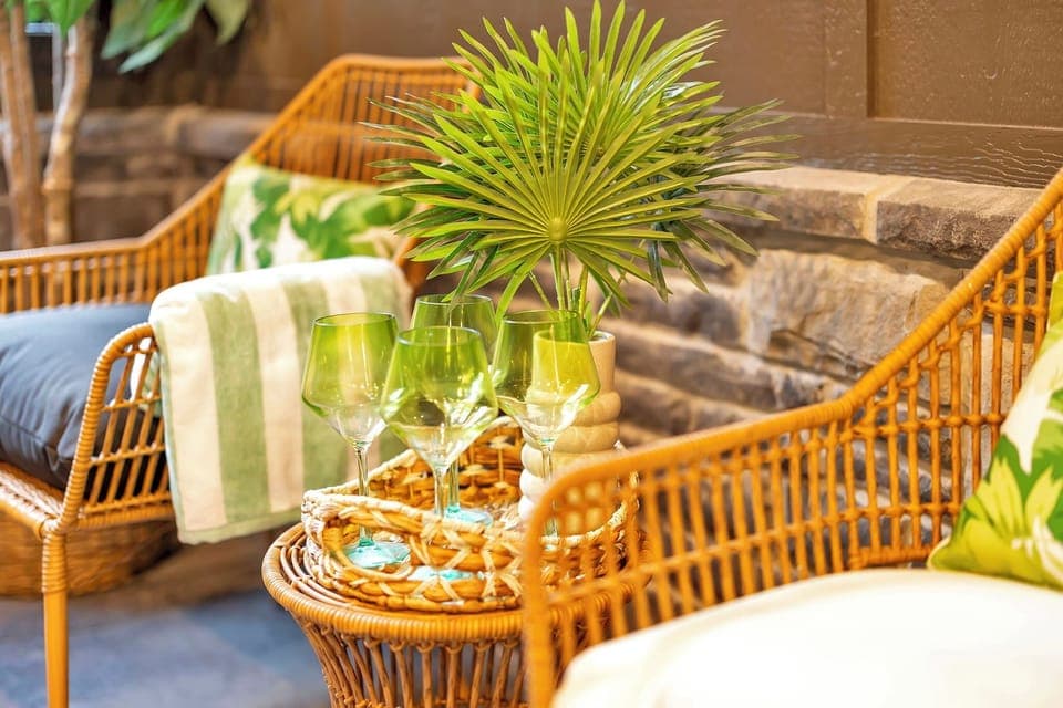 Cozy patio seating with wicker chairs, tropical decor, and green glassware.