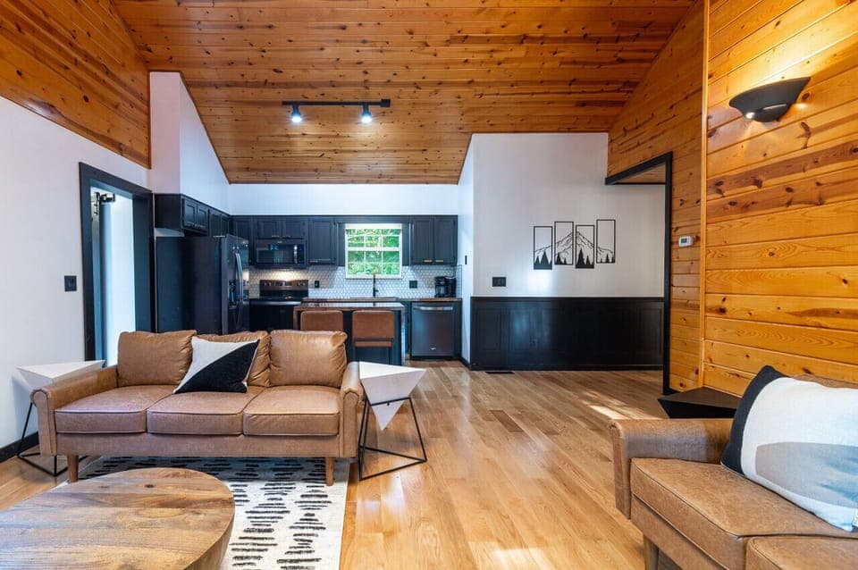 Modern cabin interior with open-concept kitchen, cozy seating, and rustic charm!