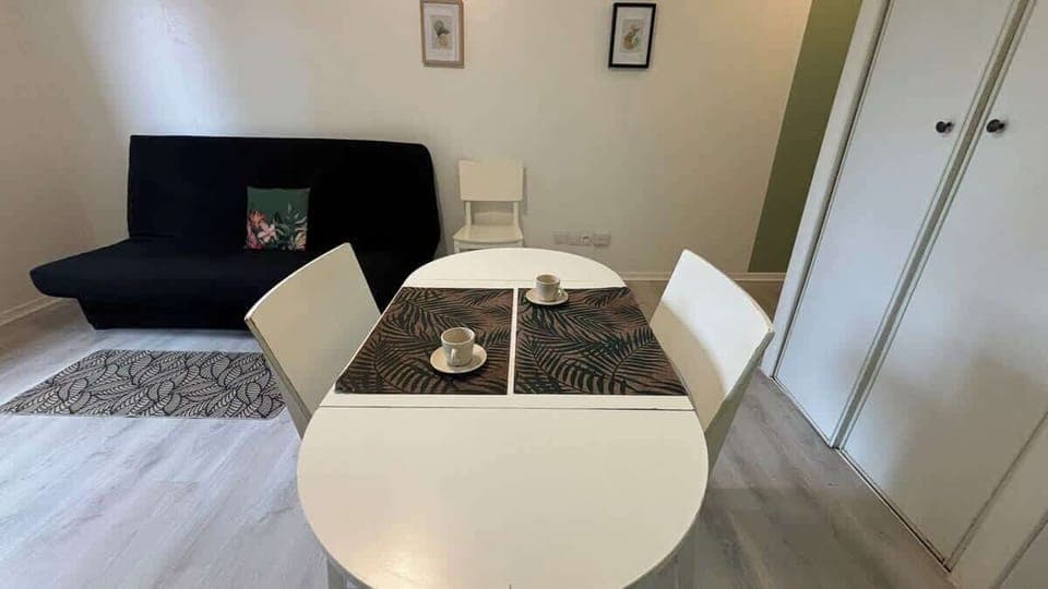 Coin repas pour deux personnes séparant la cuisine du salon.
Salon avec canapé convertible et télévision.
Espace de cuisine équipée avec petit réfrigérateur, micro-ondes, machine à café et plaques de cuisson.