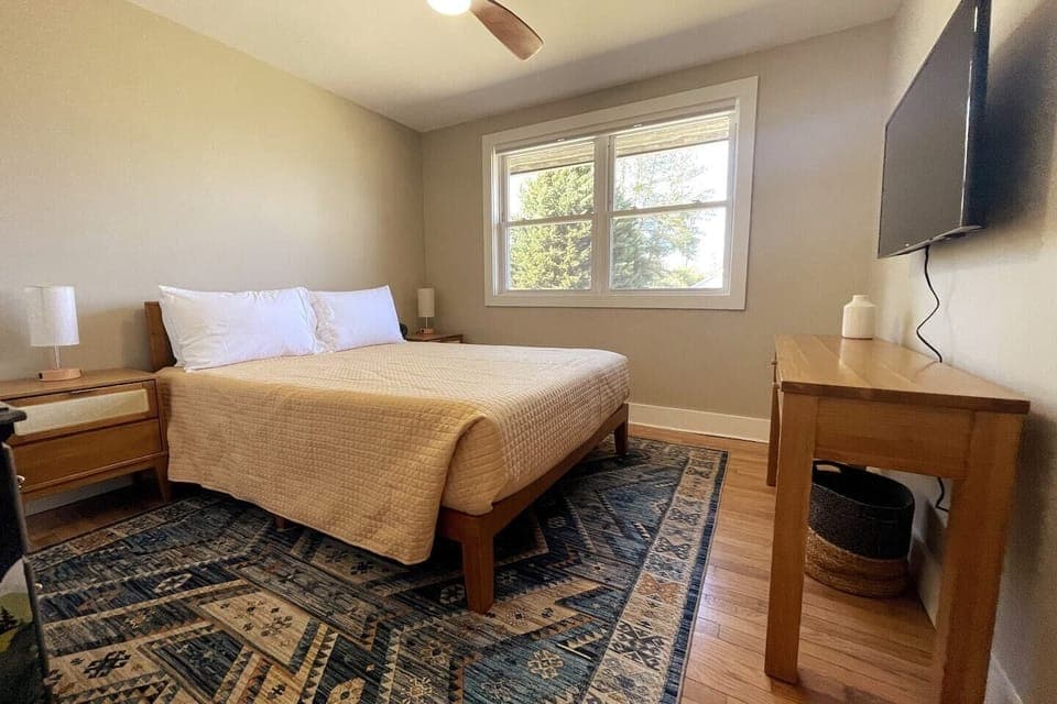 Queen bed with bedside lamps and Smart TV.