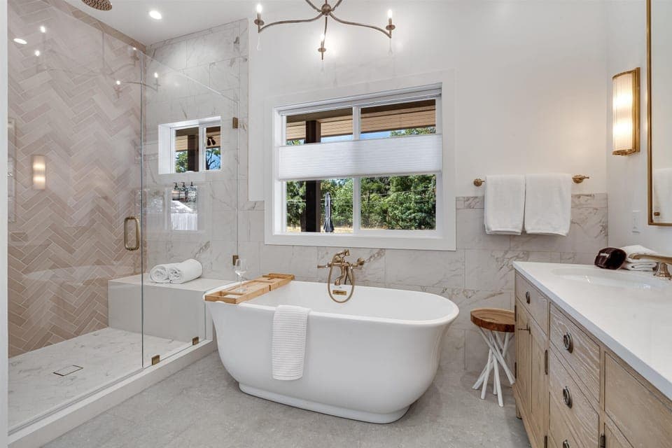 This luxurious primary bath has a soaking tub, white oak dual vanity, rain shower & toilet room. The ensuite exudes resort-like luxury.