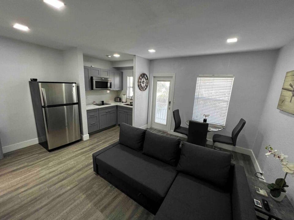 Living room and fully furnished kitchen with microwave stove.